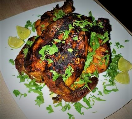 Oven roasted chicken with lime wedges on a white plate.