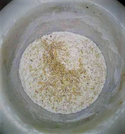 A bowl with flour, rosemary, and seeds in it.