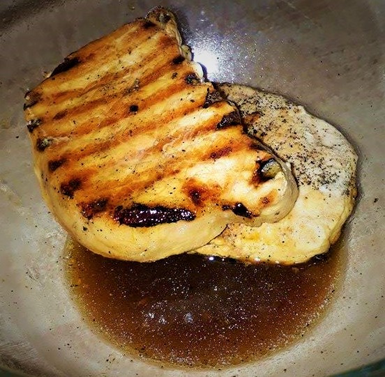 Grilled pork tenderloin in a bowl with sauce.
