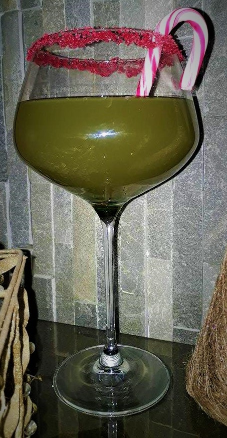 A green cocktail with a candy cane on top.