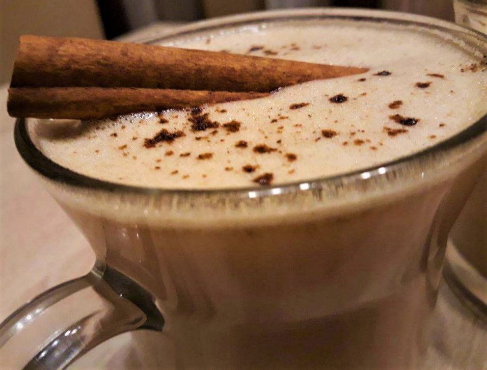 A cup of coffee with cinnamon sticks.