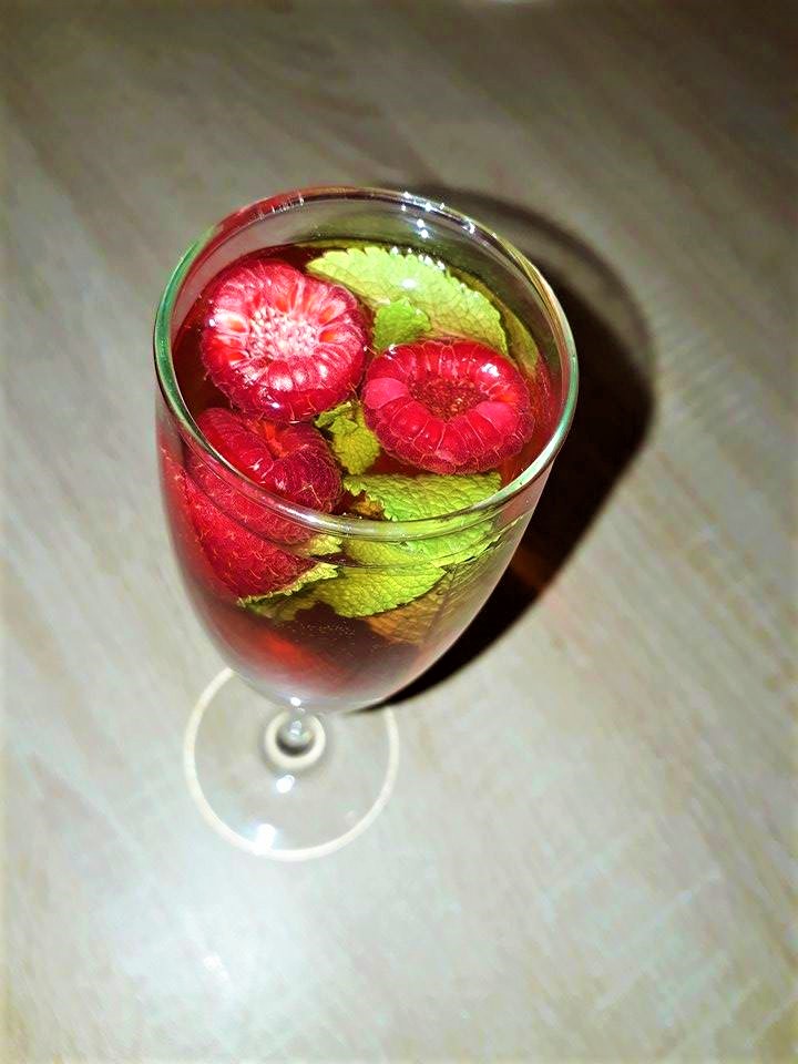 Cranberry champagne cocktails garnished with raspberries and mint.