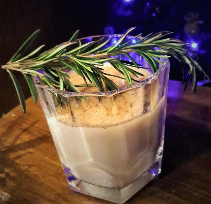 A honey-infused cocktail garnished with a rosemary sprig.