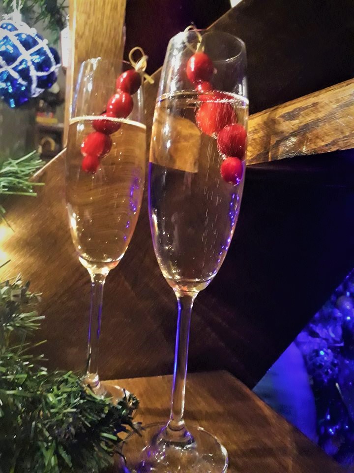 Two glasses of champagne on a table next to a christmas tree.